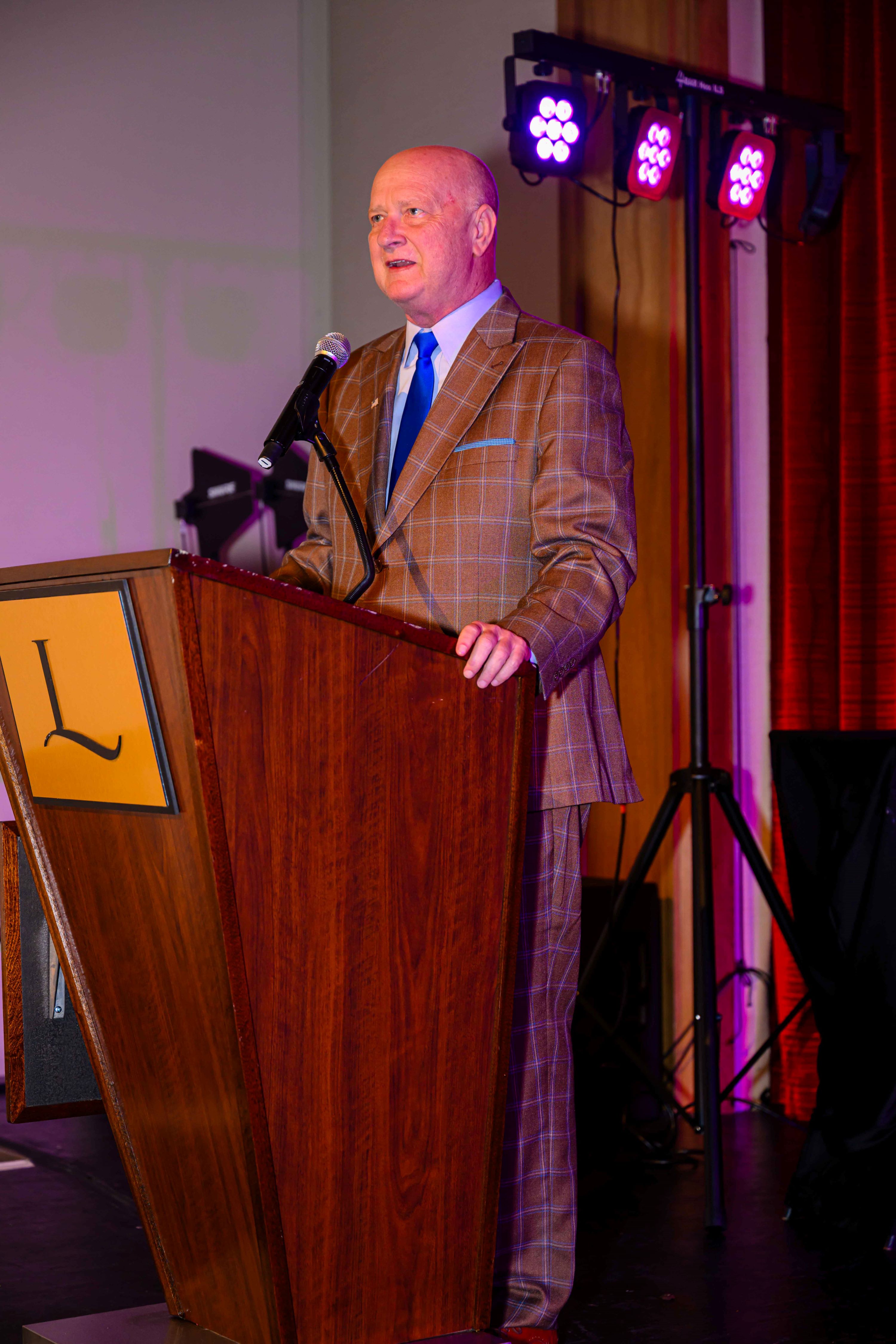 Speaker in a plaid suit at the podium